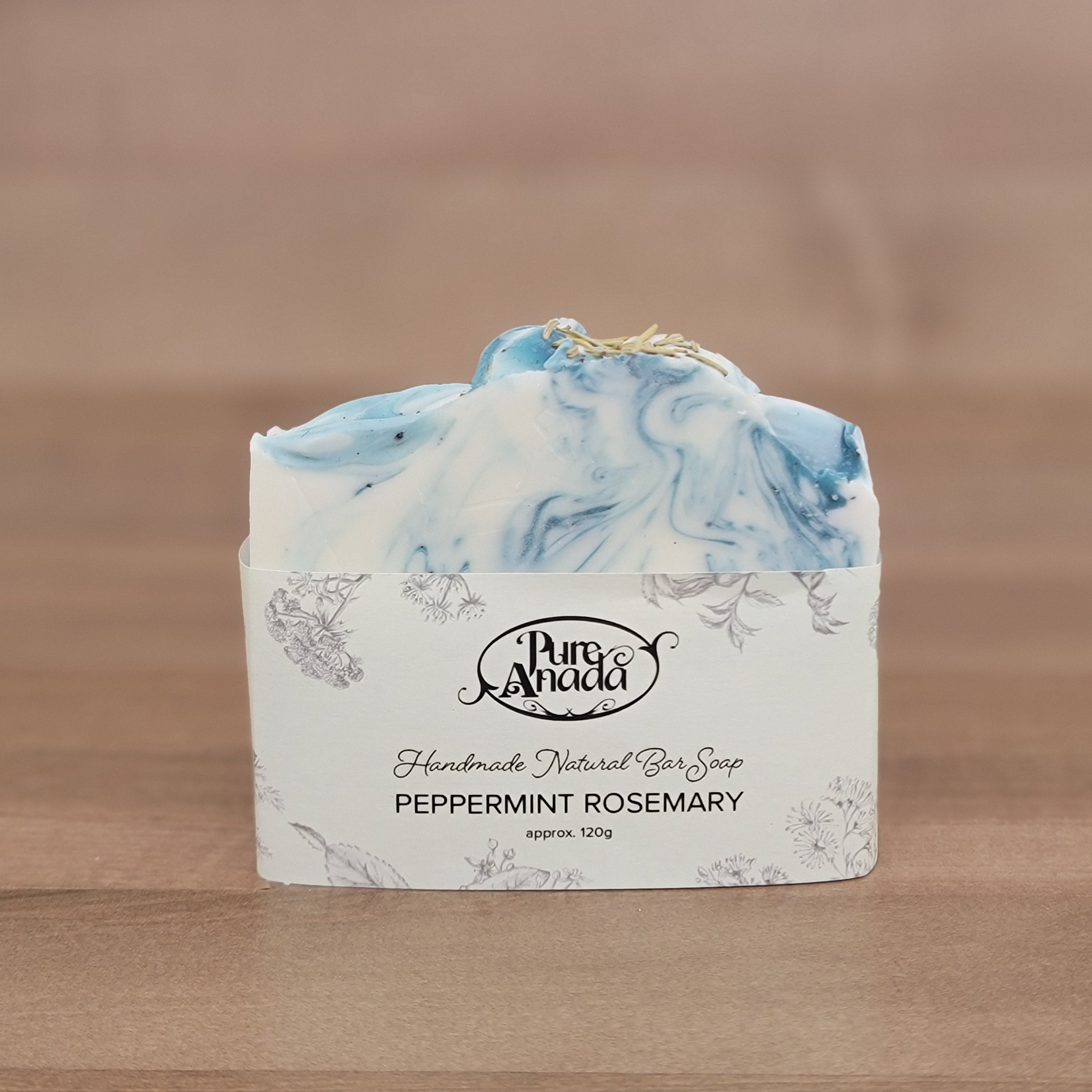 Bar of peppermint rosemary handmade natural bar soap with a decorative label on a wooden surface